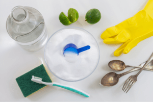 Cleaning materials: Alcohol bottle, baking soda, lime, gloves, spoon and fork, sponge and toothbrush